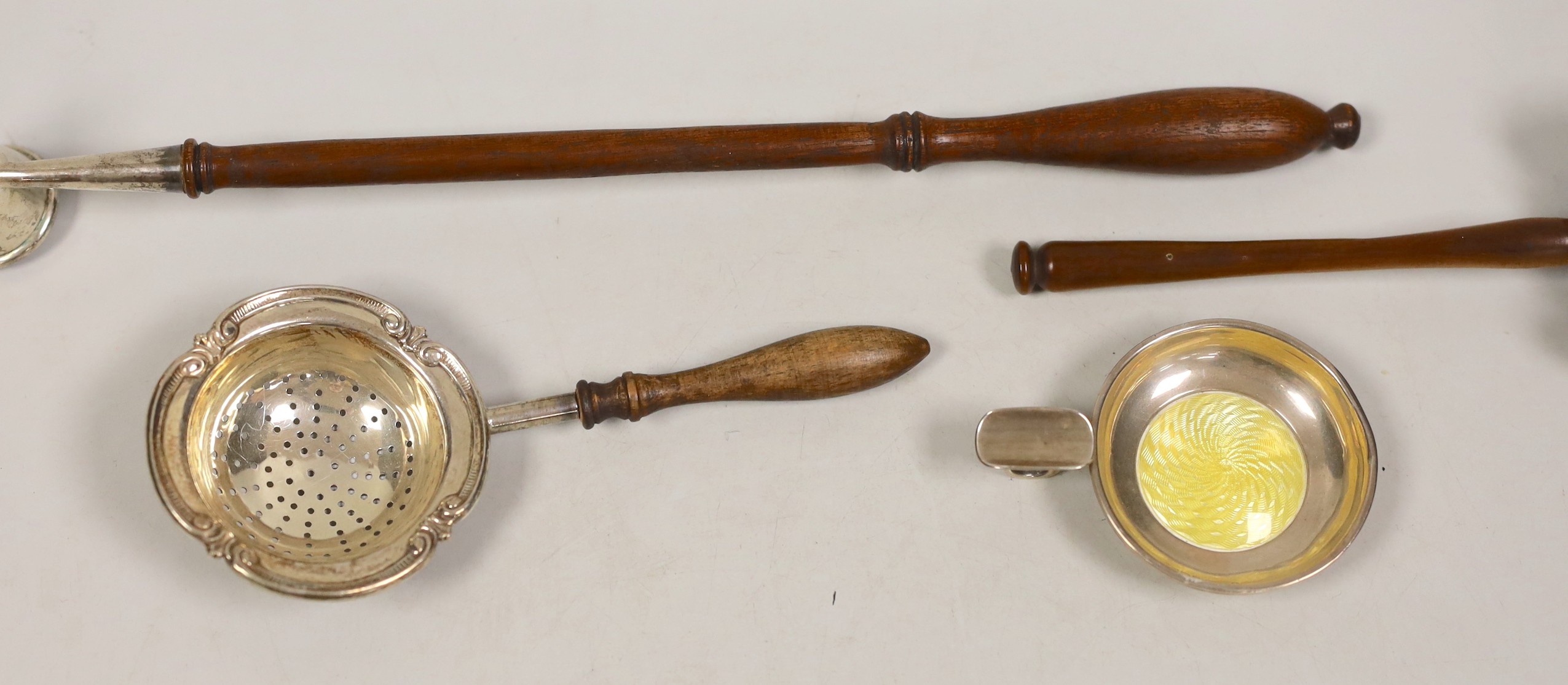 A George V silver extinguisher, with turned wooden handle, 30.8cm, a silver tea strainer, a silver and enamel ashtray and a wooden gavel.